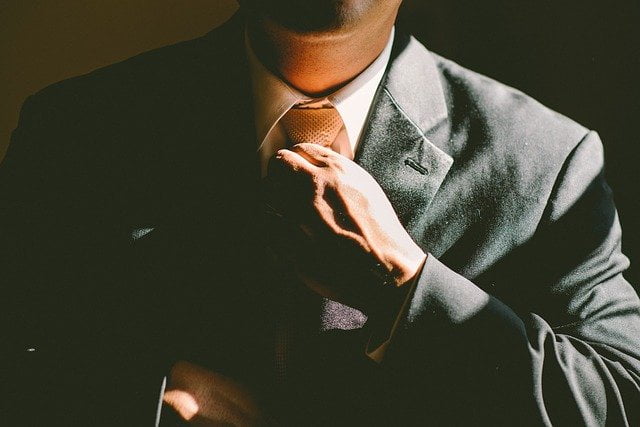 Business man adjusting tie in dark lighting