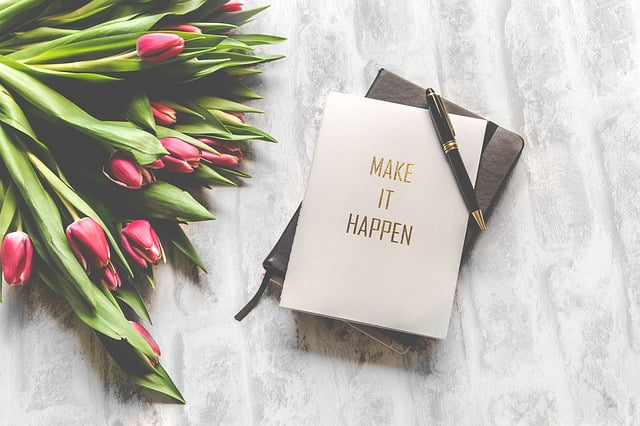 Make Things Happen notebook beside flowers