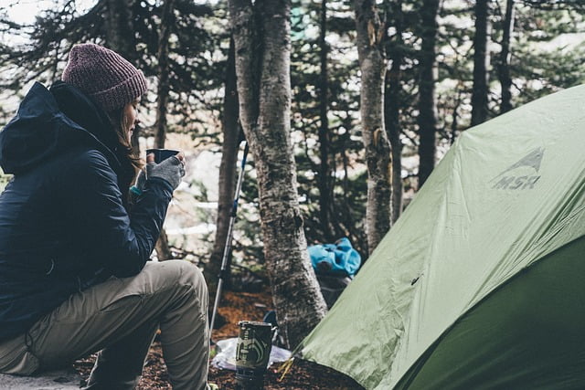 Camping woman outside tent drinking coffee