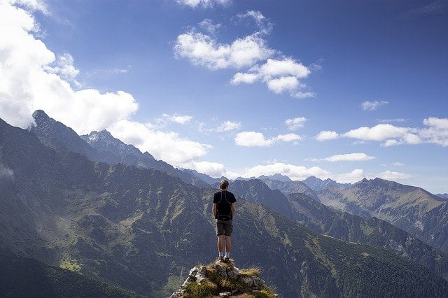 Man standing on cliff's edge overlooking mountains